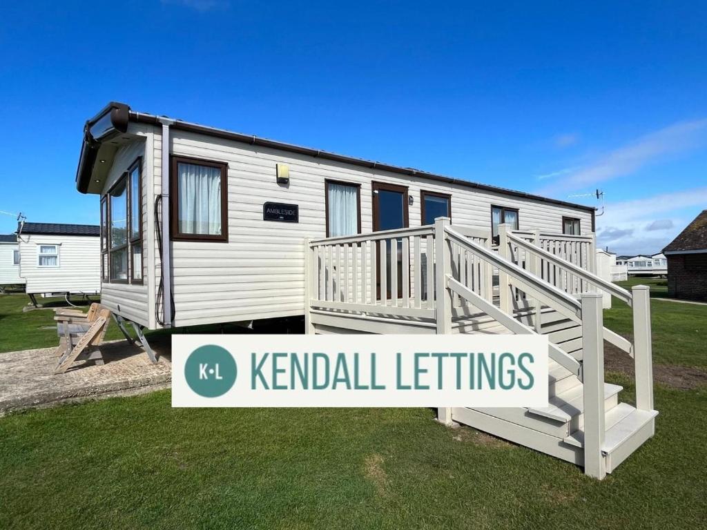 un remolque blanco con un cartel delante en Amble Retreat, Seal Bay Resort, en Selsey