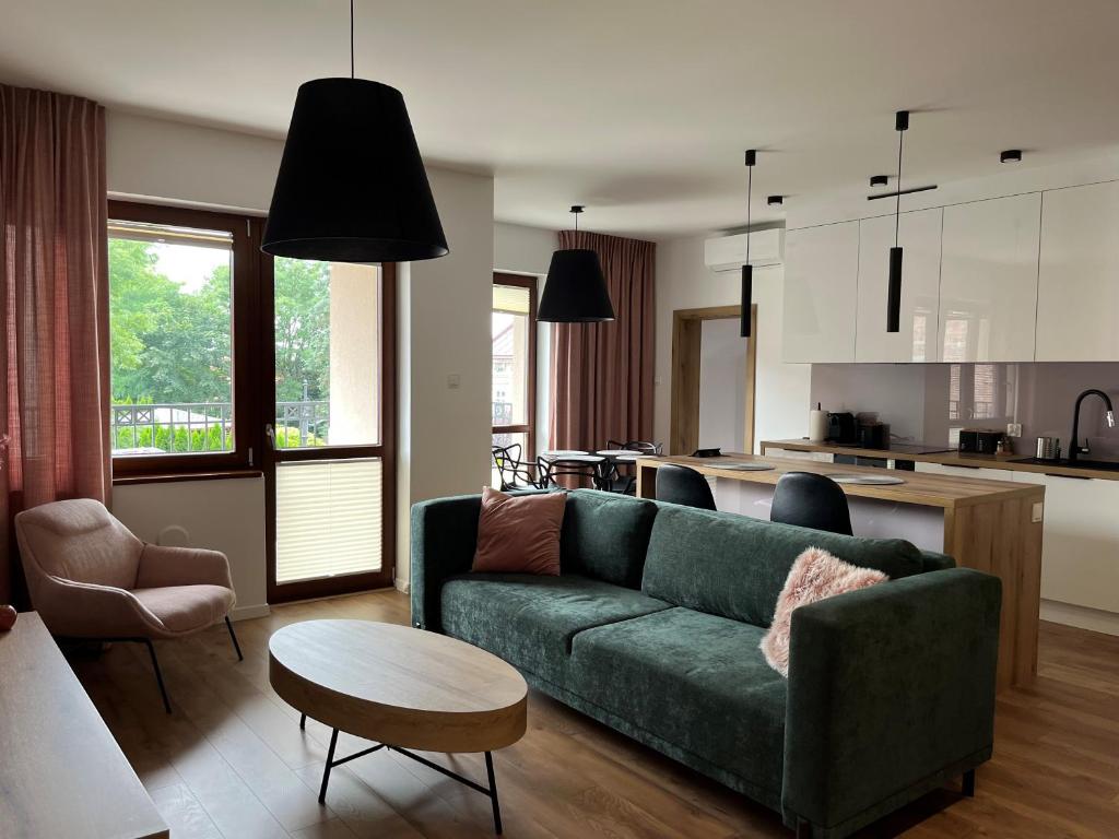 ein Wohnzimmer mit einer grünen Couch und einem Tisch in der Unterkunft Willa Matejki - Apartament 7 in Przemyśl