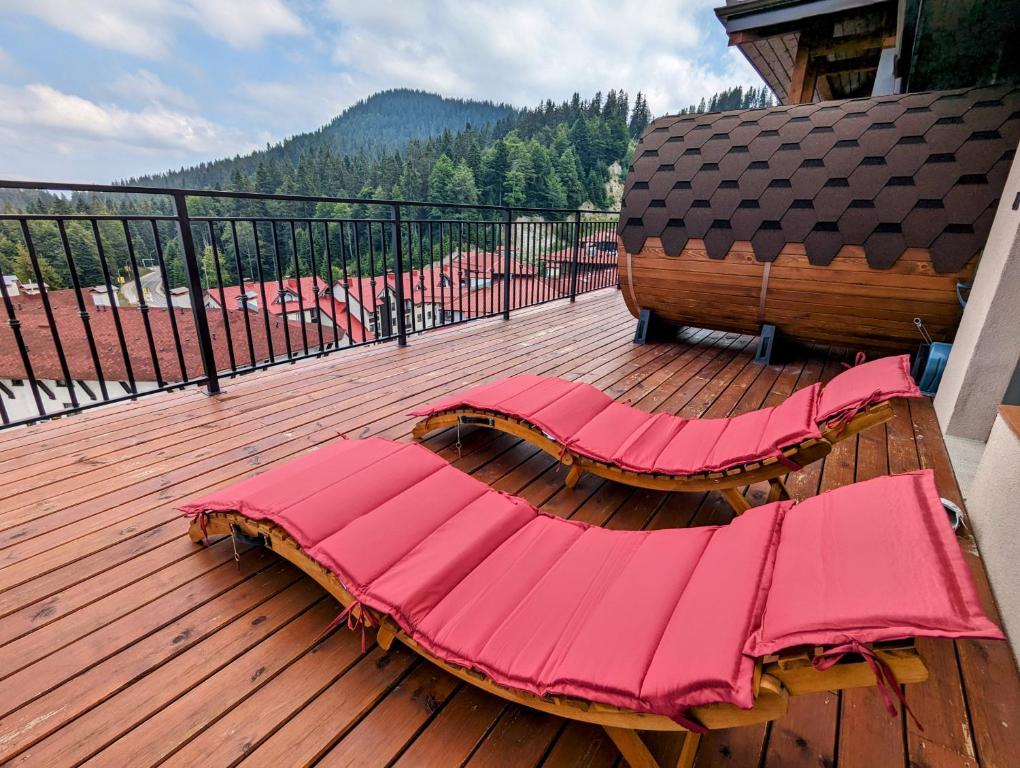 a wooden deck with pink cushions on a balcony at Pine & Wine Sauna Apartment in Pamporovo