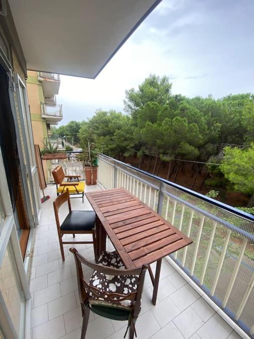 patio con mesa de madera y sillas en el balcón en Appartamento vista mare, en Campomarino