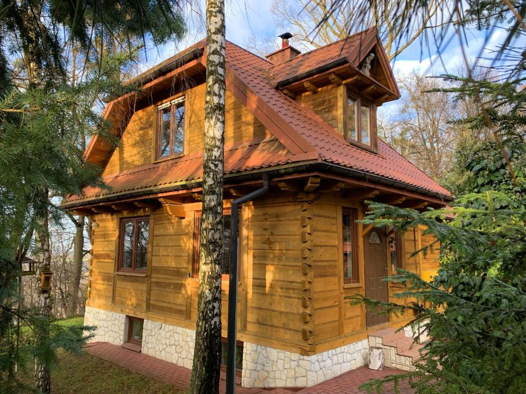 a log cabin in the woods with a red roof at Dom na Zamkowej in Kazimierz Dolny