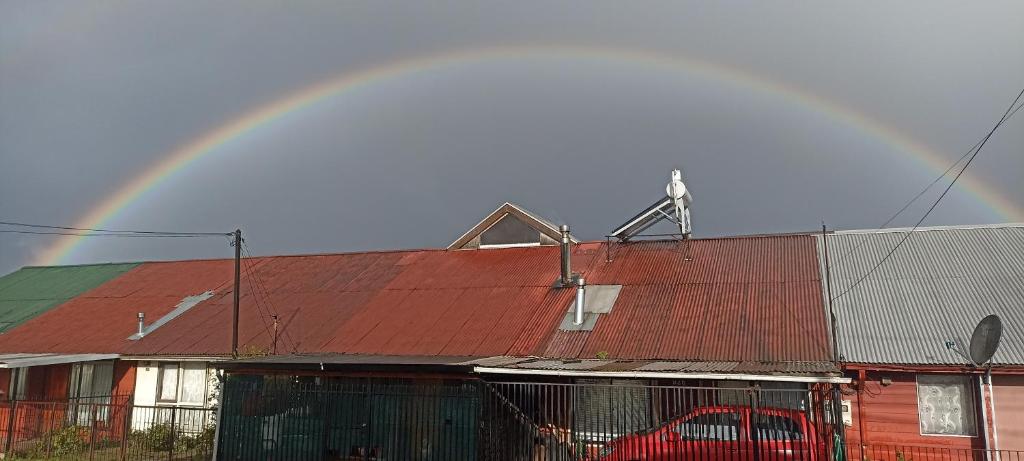 ein Regenbogen über einem Gebäude mit rotem Dach in der Unterkunft Hostal doña marta in Valdivia