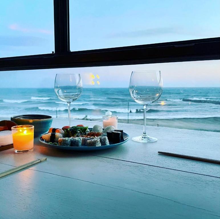 una mesa con un plato de comida y dos copas de vino en Primera linea de Playa de Martina en Almerimar