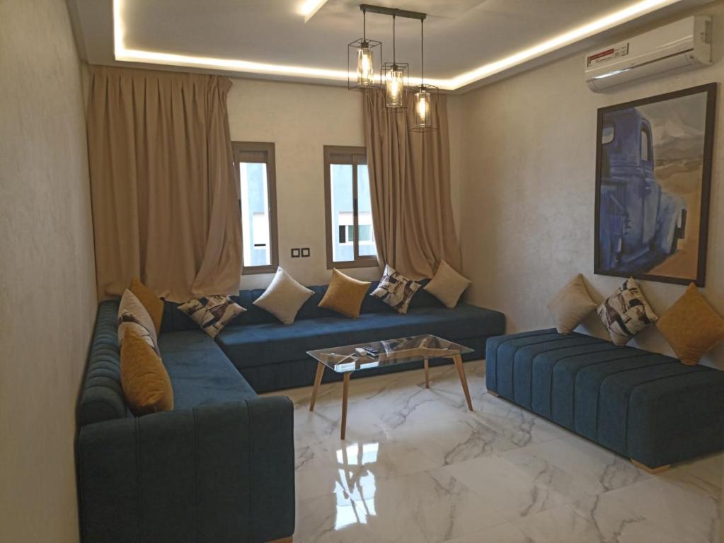 una sala de estar con 2 sofás azules y una mesa. en Appartement luxueux proche de tout, en Fez