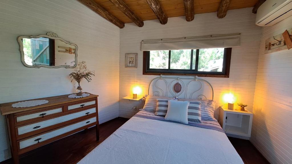 1 dormitorio con cama blanca y ventana en Cabañas Bahia Serena, en Punta del Diablo