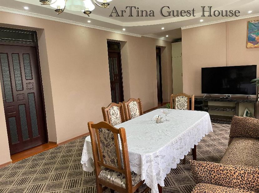 comedor con mesa, sillas y TV en Artina Guest House, en Tatʼev