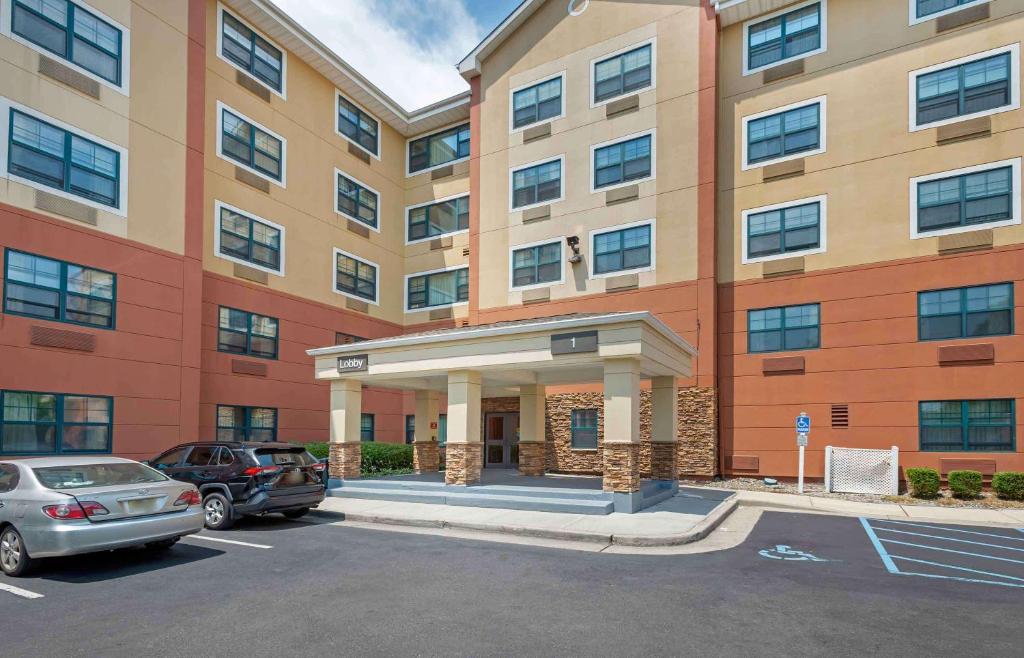 un gran edificio con coches estacionados en un estacionamiento en Extended Stay America Suites - Secaucus - Meadowlands, en Secaucus