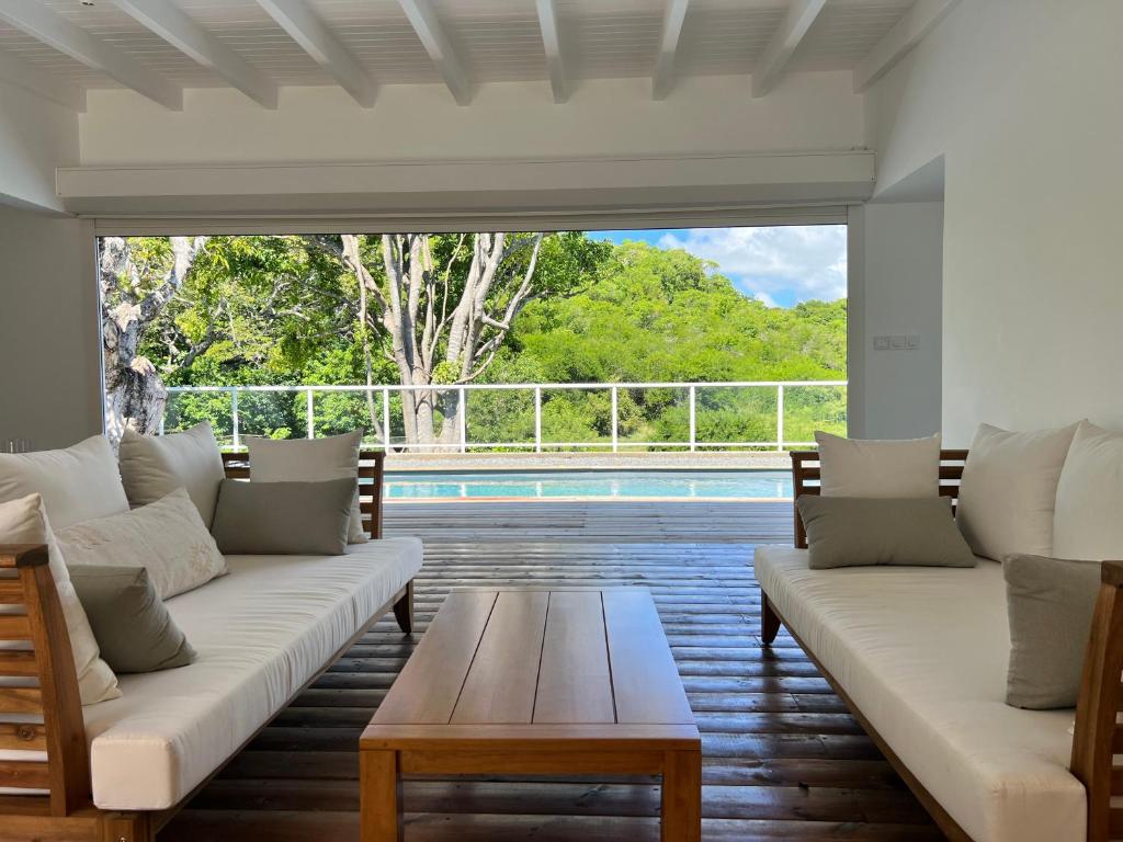 sala de estar con sofás, mesa y piscina en Bienvenue à la Villa Ifè en Le Gosier