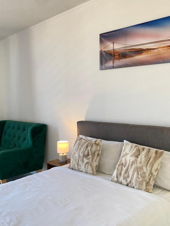 a bedroom with a bed and a green chair at Yolé Apartment - City 101 in Windhoek