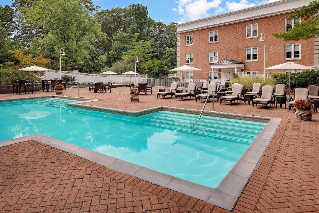 uma piscina com cadeiras e mesas em frente a um edifício em The Westin Governor Morris, Morristown em Morristown