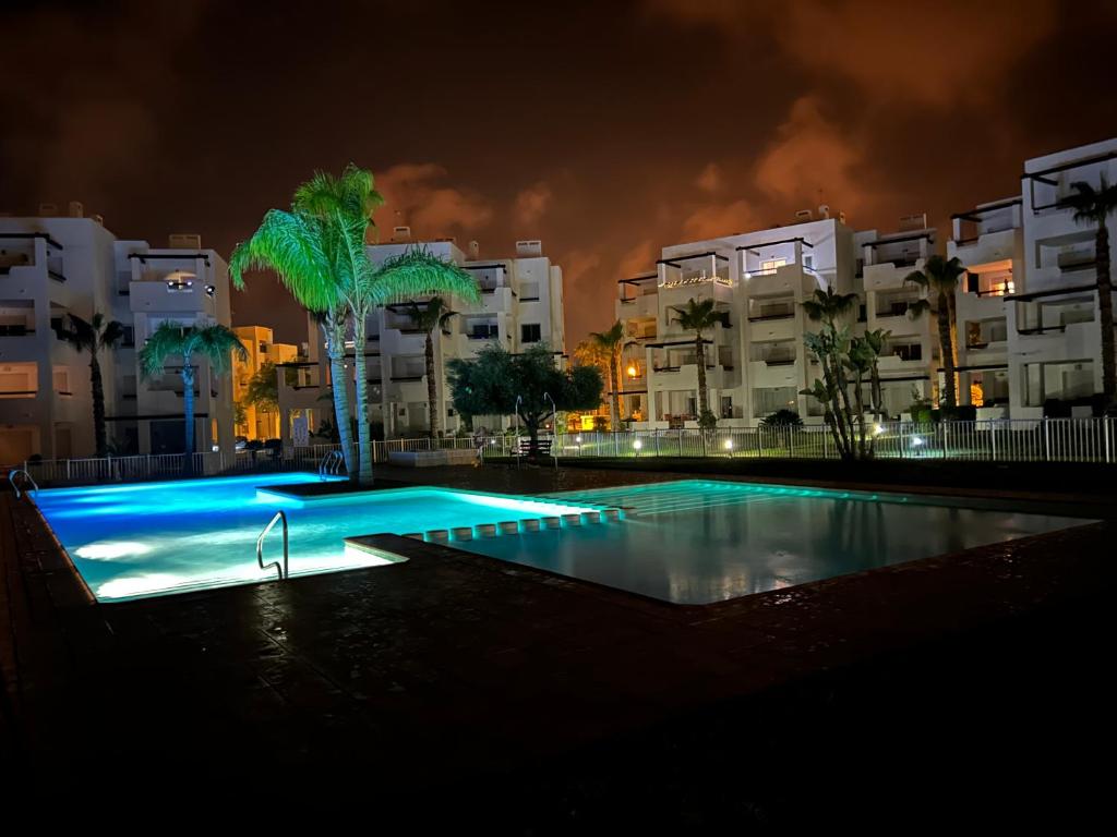 - une piscine de nuit avec des palmiers et des bâtiments dans l'établissement Casa Siska, à Torre-Pacheco