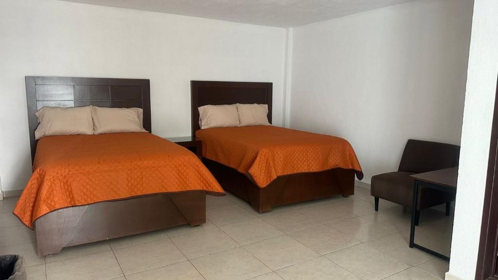 Zimmer mit 2 Betten und einem Stuhl in einem Zimmer in der Unterkunft CASA BRAVO in Huamantla