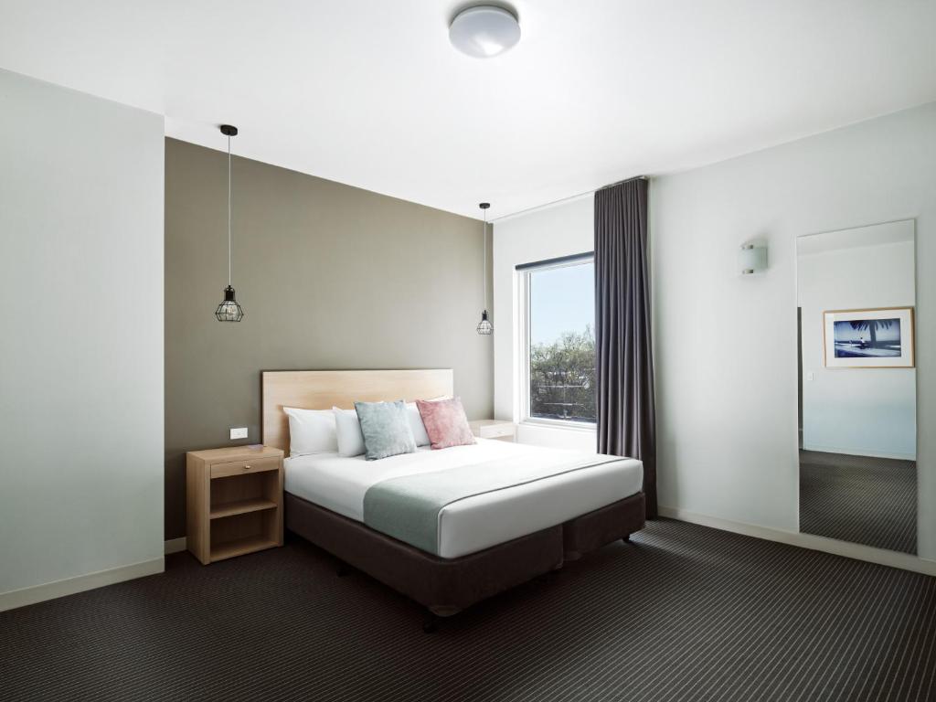 a bedroom with a bed and a large window at Saint Kilda Beach Hotel - formerly Rydges St Kilda in Melbourne