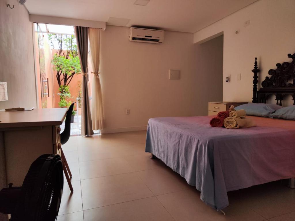Schlafzimmer mit einem Bett, einem Schreibtisch und einem Fenster in der Unterkunft Casa Sagrada 282 in Fortaleza