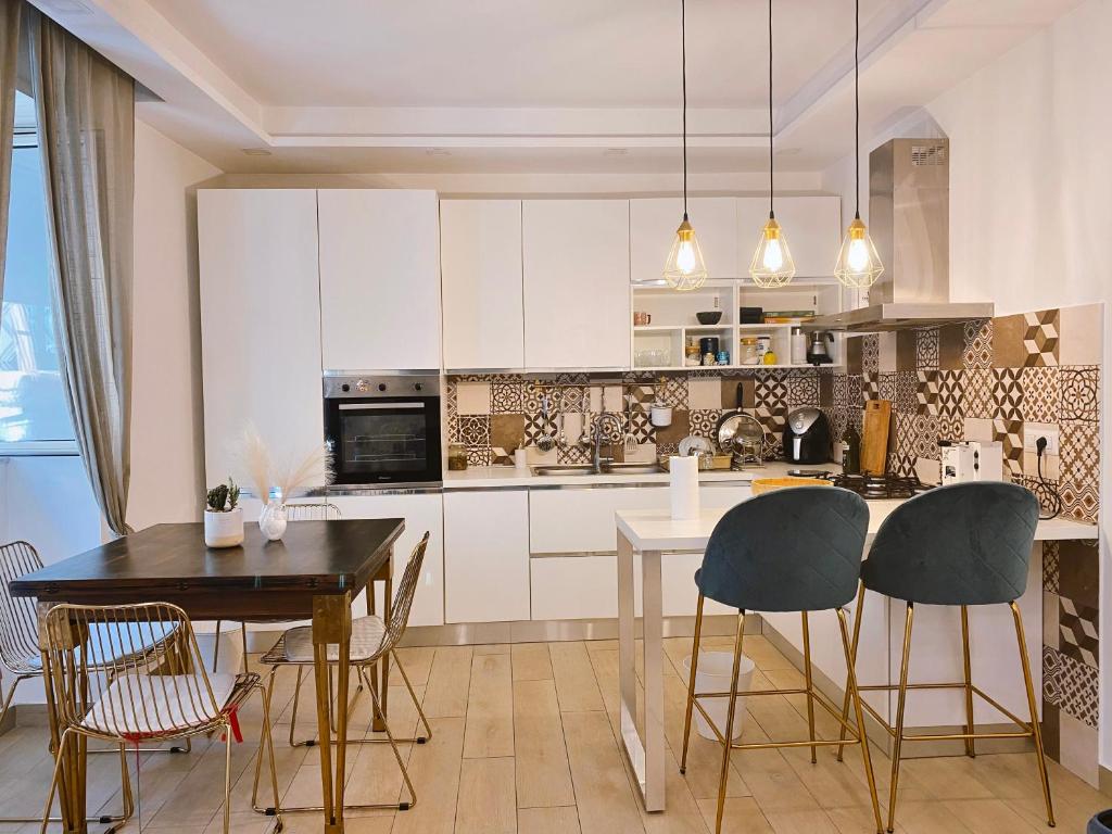 a kitchen with white cabinets and a table and chairs at Fifi Home in Pozzuoli