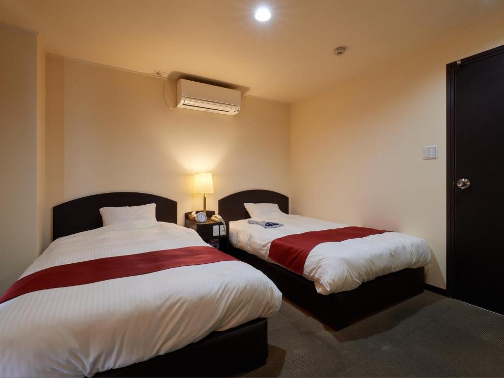una habitación de hotel con 2 camas en una habitación en Hotel SIMIZU en Tokamachi