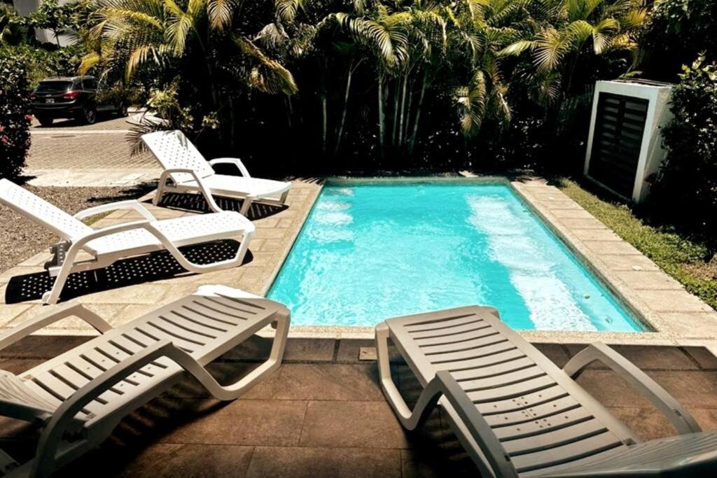 a swimming pool with two lounge chairs and a swimming pool at Lapa House 4 ( Cozy pool-3 bedrooms(LL#4) in Jacó