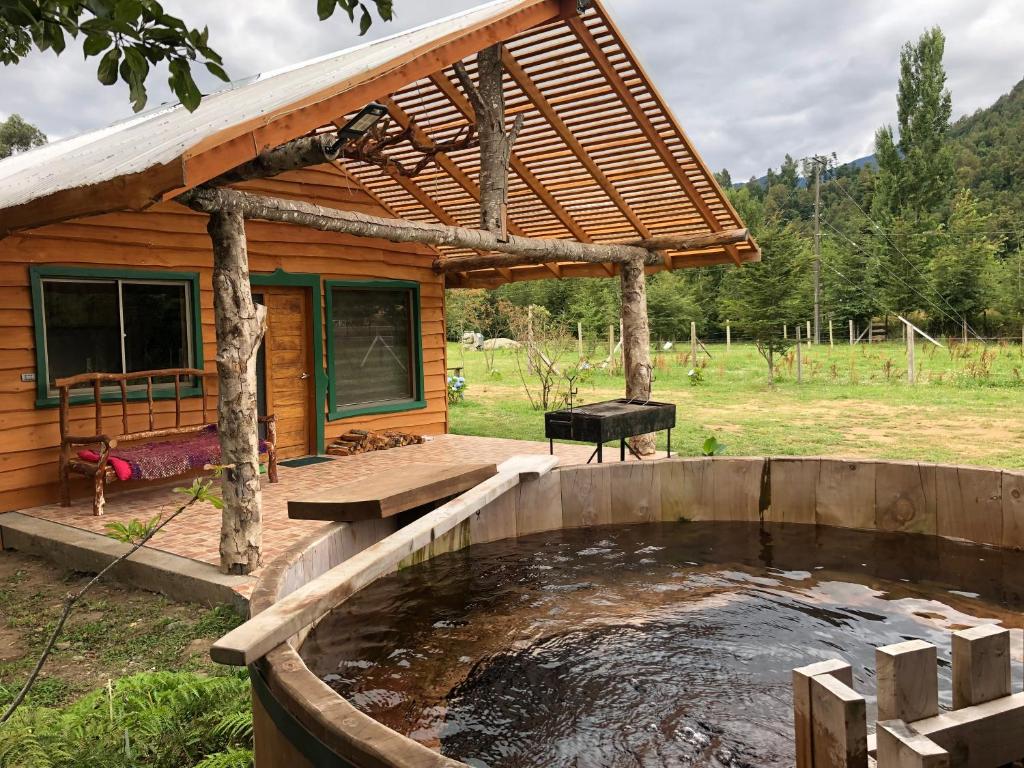 einem Teich vor einer Blockhütte in der Unterkunft Refugio Wanglen Cabañas y Tinajas hidromasaje in Lago Ranco