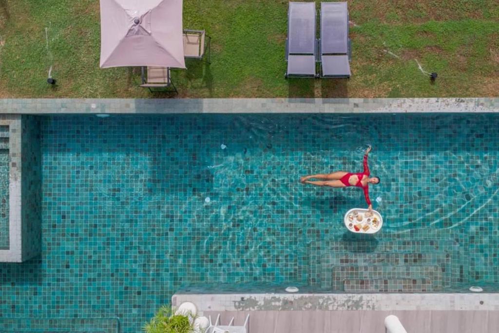 een zwembad met een vrouw op een stoel in het water bij Viva Montane Hotel Pattaya in Pattaya South