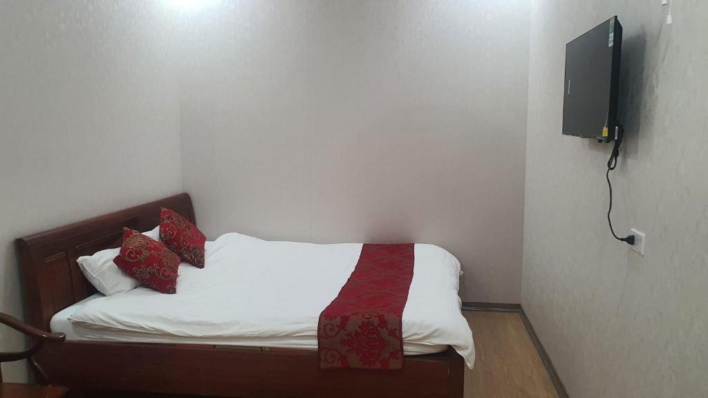 um pequeno quarto com uma cama e uma televisão na parede em Linh Hằng hotel em Ha Giang
