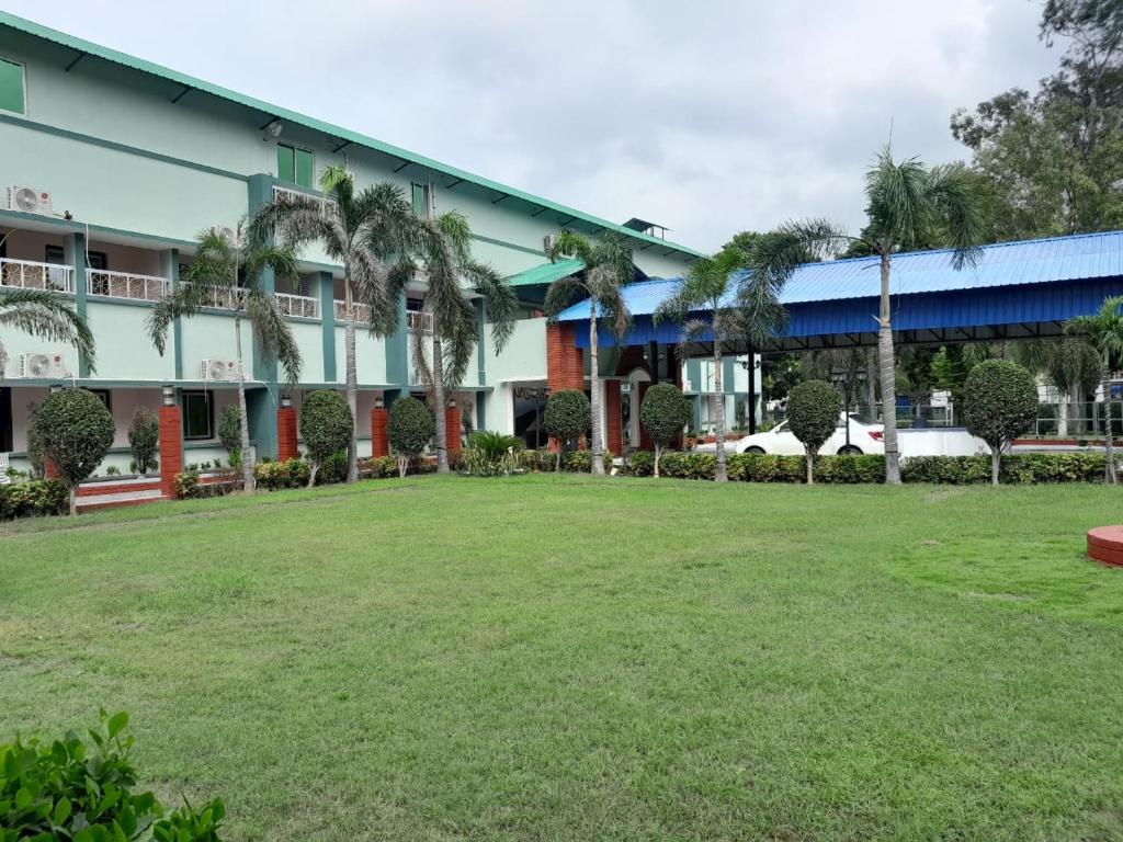 a building with palm trees in front of a yard at Aarunya Hotel And Resort in Rājgīr