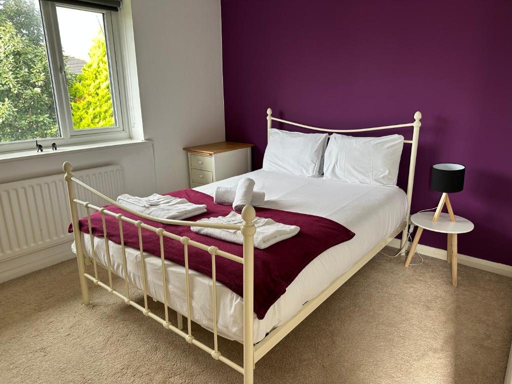 Manchester 2 Bedroom House with Garden في مانشستر: غرفة نوم مع سرير مع جدار أرجواني