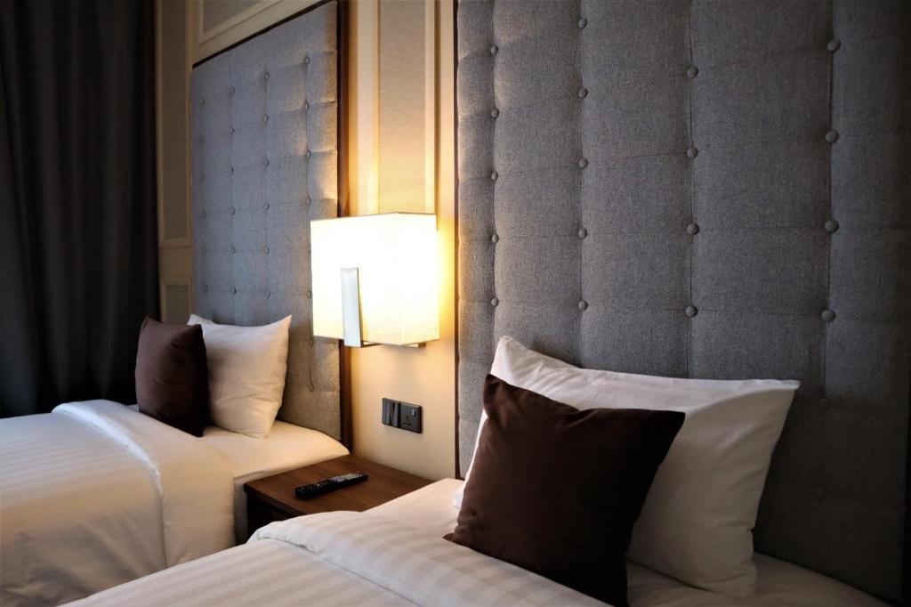 a hotel room with two beds and a lamp at KSL ESPLANADE HOTEL with HOT SPRING in Klang