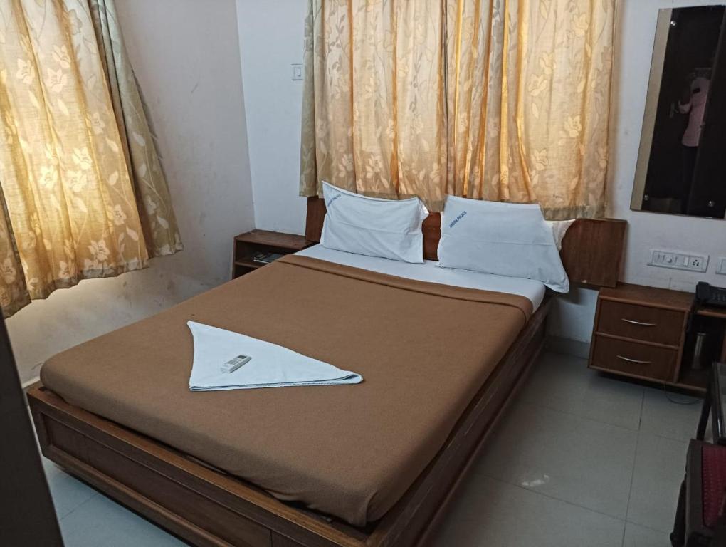 um quarto com uma cama grande e uma colcha castanha em Hotel Ambika Palace em Chennai