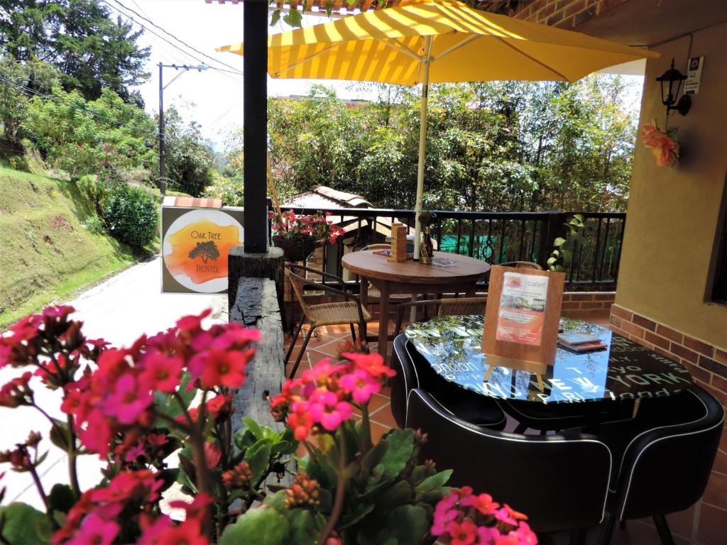 a patio with a table and umbrella and flowers at Oak Tree house in Guatapé