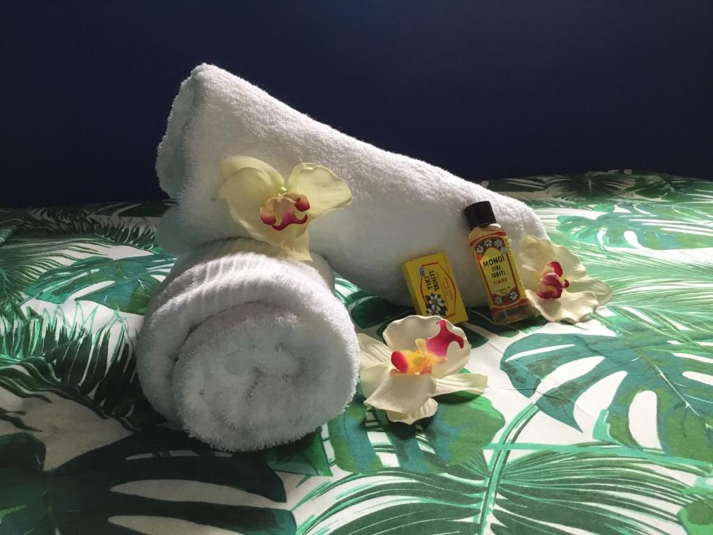 ein Handtuch und eine Flasche Seife und Blumen auf dem Bett in der Unterkunft Belle Maison F3 in Papeete