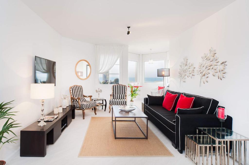 a living room with a black couch and red pillows at Chic 3BR Apt w Parking on the Beach by Sea N' Rent in Tel Aviv