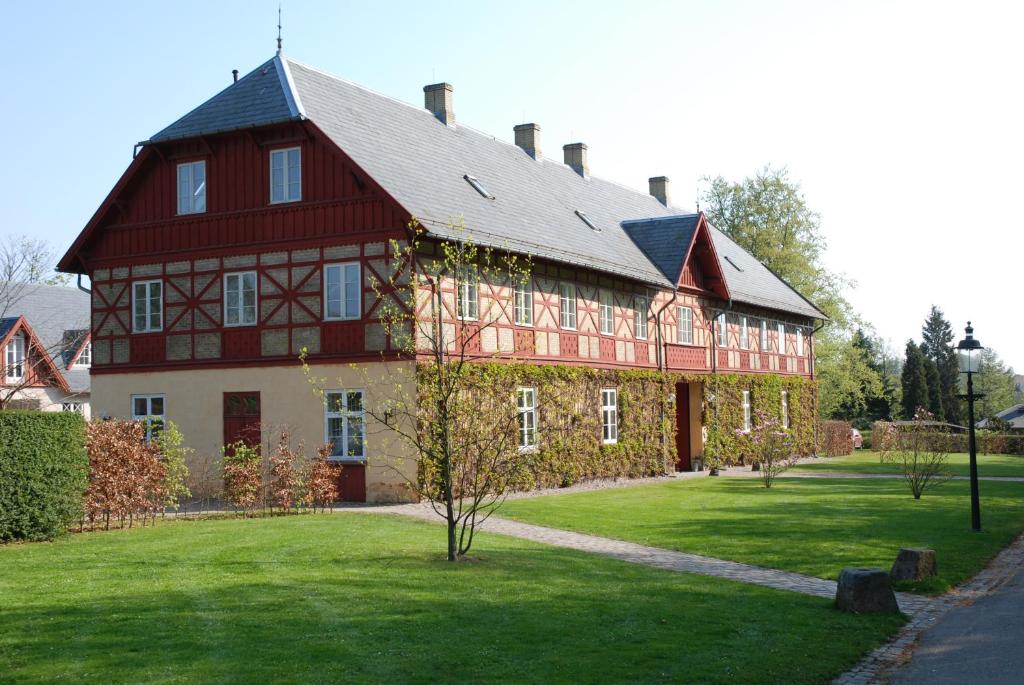 ein großes rotweißes Gebäude auf einem grünen Rasen in der Unterkunft Bernstorff Castle Hotel in Gentofte