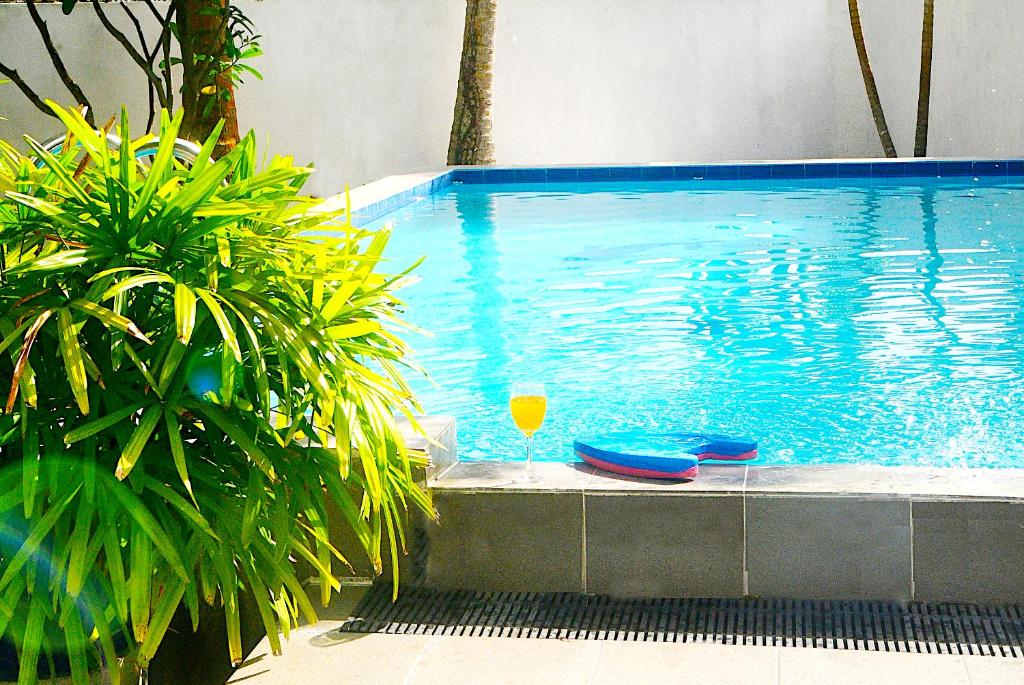a swimming pool with a glass of wine next to it at Calm Villa Wadduwa in Wadduwa