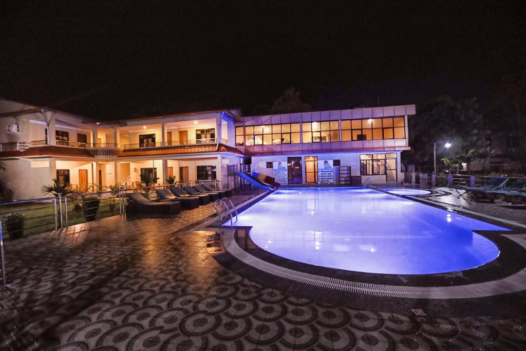 a large swimming pool in front of a building at night at Hotel Wildlife Camp in Sauraha