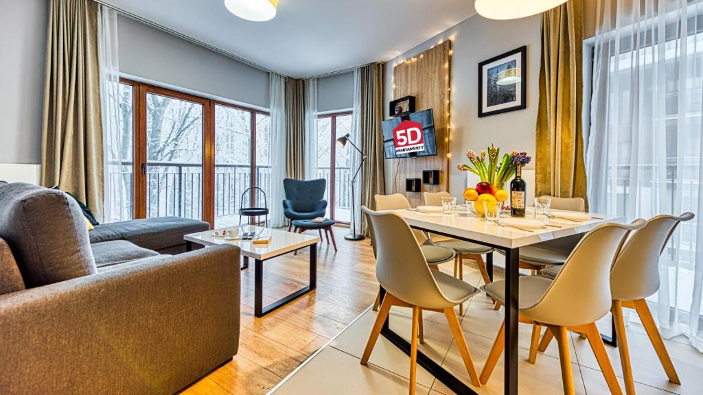ein Wohnzimmer mit einem Tisch, Stühlen und einem Sofa in der Unterkunft Apartament 14 Nad Norweską Polaną z Basenem i SPA - 5D Apartments in Szklarska Poręba