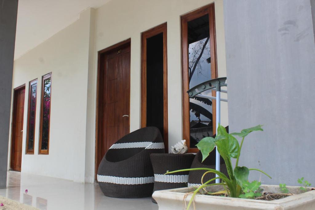 un par de sillas blancas y negras sentadas frente a una puerta en WL GUESTHOUSE, en Labuan Bajo