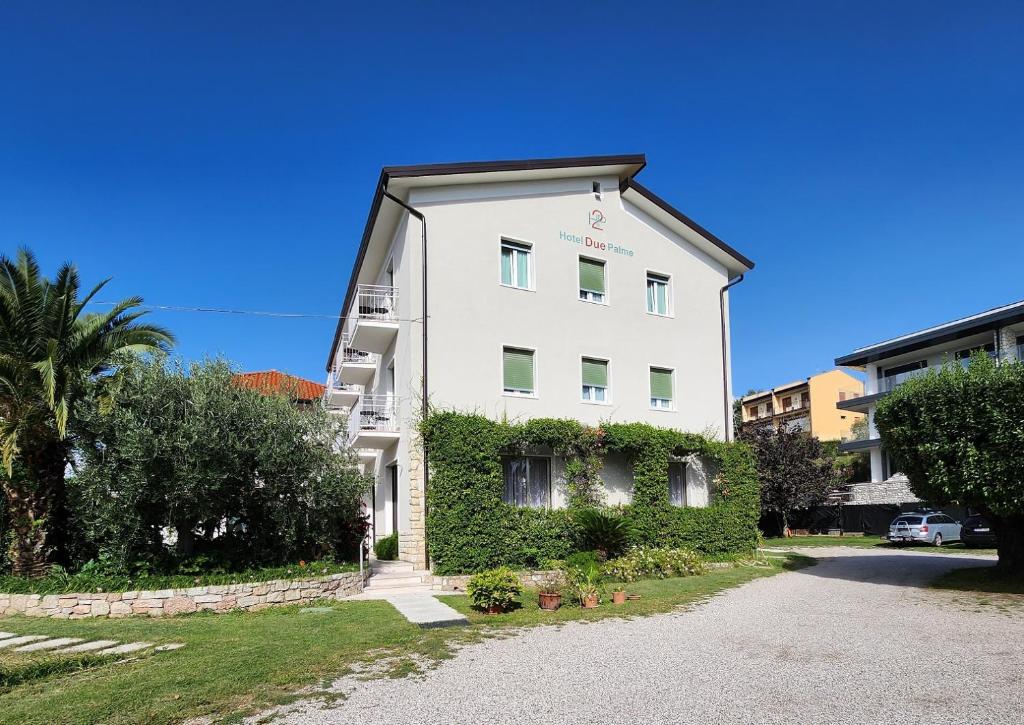 un bâtiment blanc avec du lierre sur son côté dans l'établissement Hotel 2 Palme, à Torri del Benaco