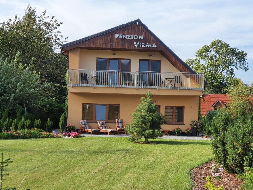 een huis met een balkon en een tuin bij Penzion Vilma in Smilovice
