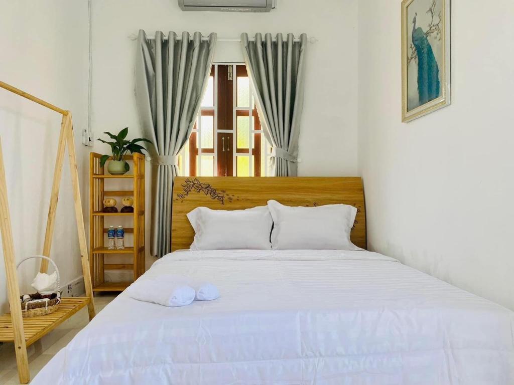 a bedroom with a bed with white sheets and a window at Nại Home Venuestay in Ninh Hải