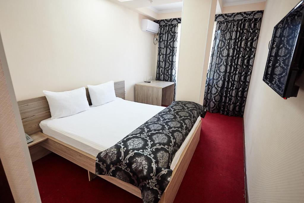 Habitación pequeña con cama y alfombra roja. en KZO Hotel en Shymkent