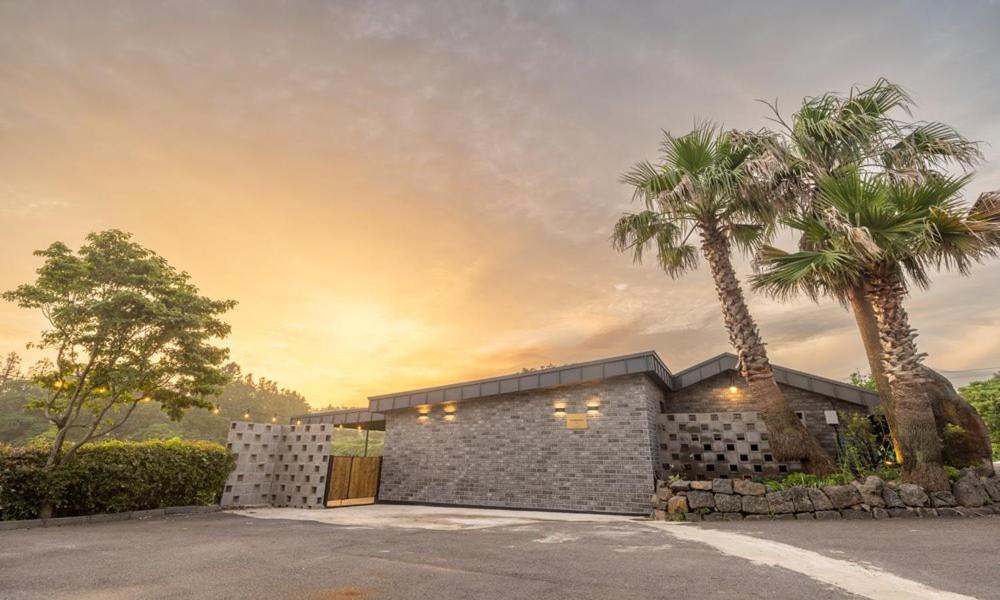a house with two palm trees in front of it at Jeju BunkerHotel&Resort in Seogwipo