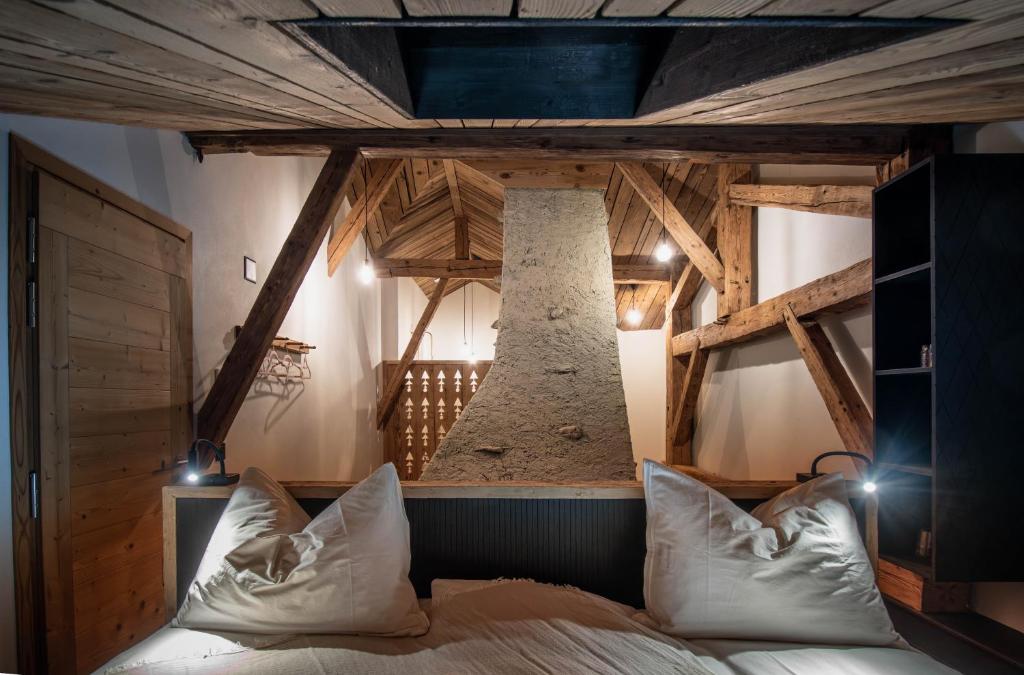 ein Schlafzimmer mit einem Bett in einem Zimmer mit Holzdecken in der Unterkunft Hôtel-Restaurant Le Cochon Rose in La Sagne