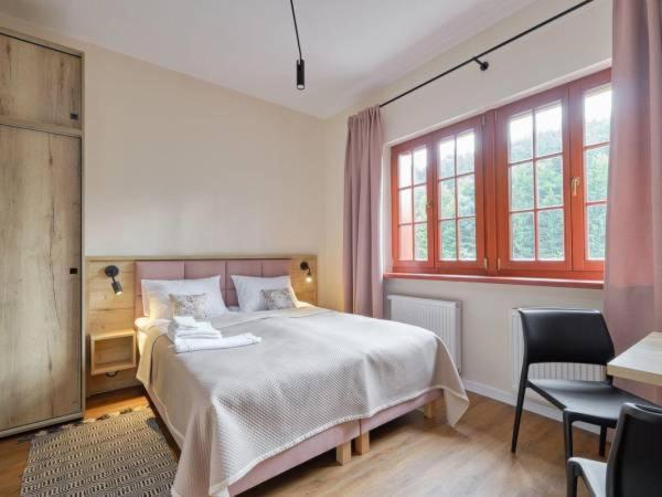 a bedroom with a bed and two chairs and windows at Villa Winkler in Miedzygorze
