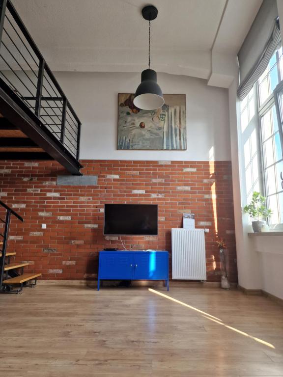 ein Wohnzimmer mit einer Ziegelwand und einem TV in der Unterkunft Loft Hiellego in Żyrardów