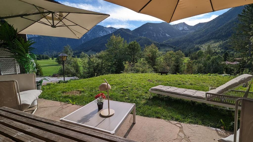 a patio with a bench and a table with an umbrella at Gemütliches Berg-Chalet mit Panoramablick in Bayrischzell