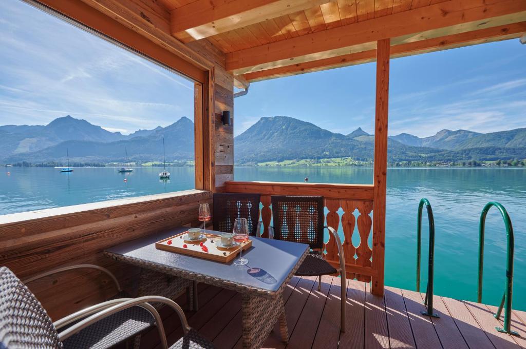 a table on a deck with a view of the water at Chalet´s am See in St. Wolfgang