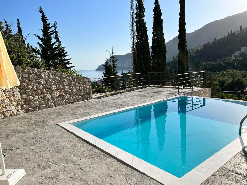 a blue swimming pool with a view of the ocean at Katerinas Village Supreme Villas with private pool in Agios Nikitas