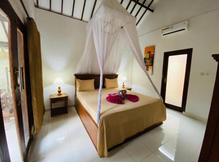 a bedroom with a bed with a mosquito net at Puring Bungalows in Gili Air