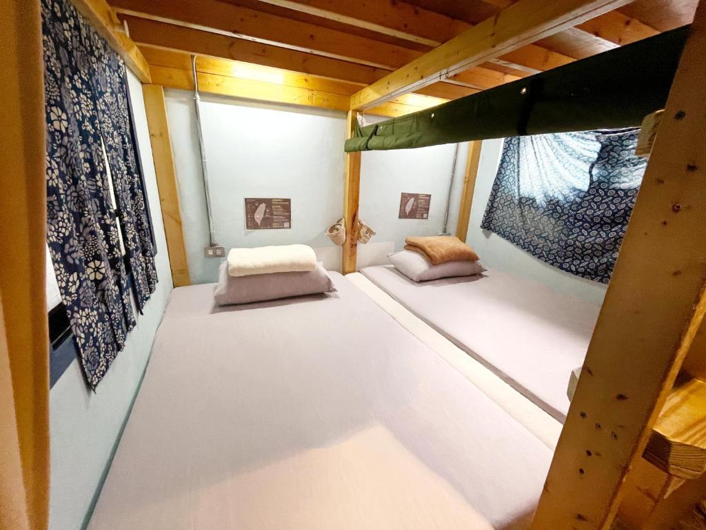 two bunk beds in a room with a window at Fuqi Hostel - Heping in Tainan