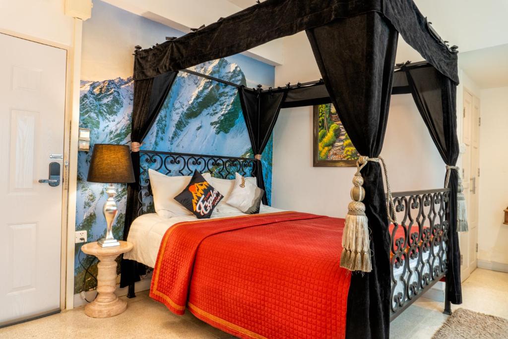 Ban Si Than的住宿－The White Rabbit Hostel，一间卧室配有一张带红色毯子的天蓬床